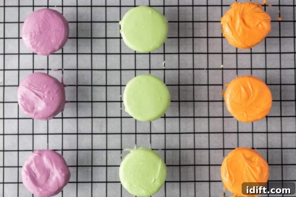 Nine perfectly coated round cookies, presenting a colorful array of purple, green, and orange, neatly arranged on a black cooling rack which is placed over parchment paper.