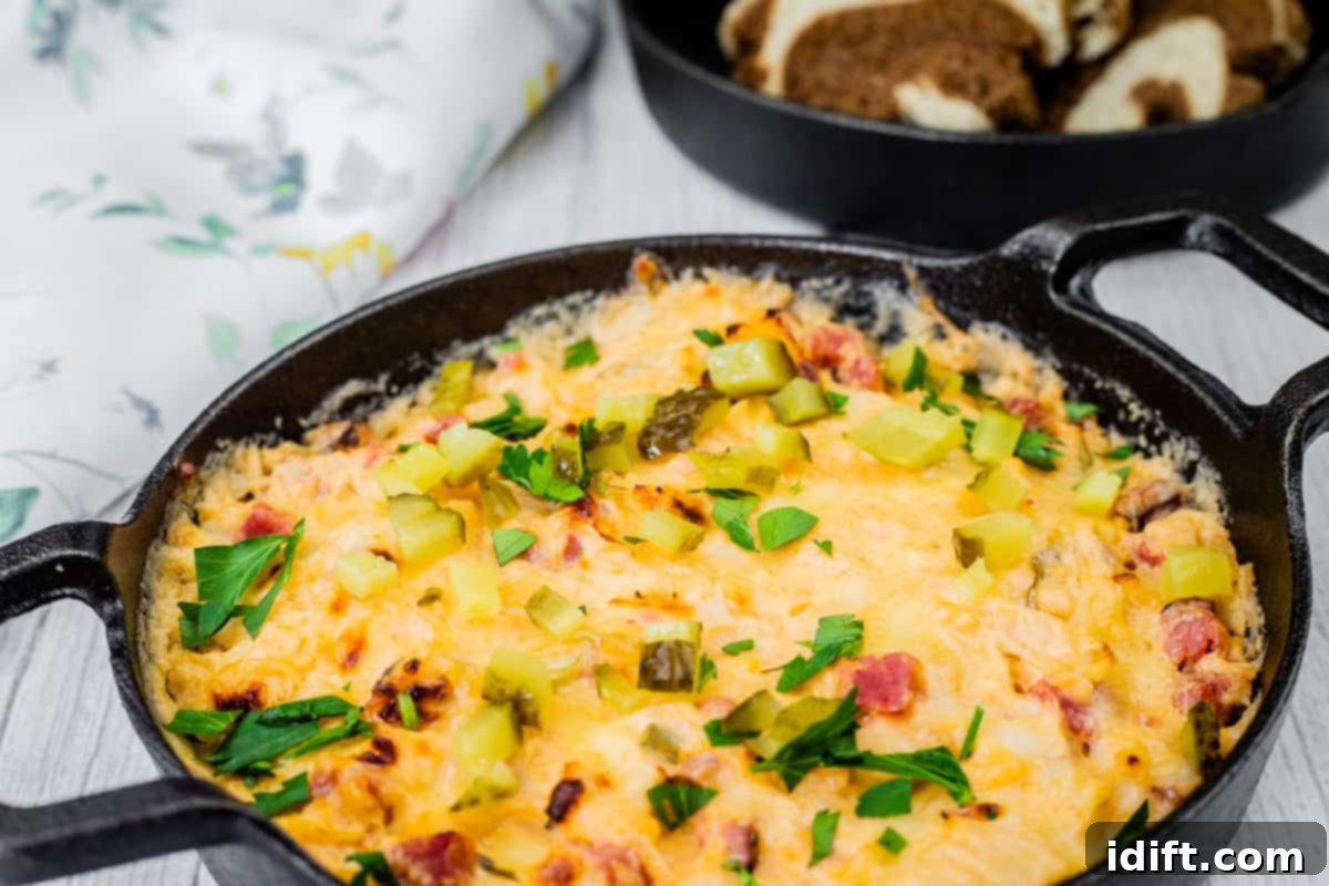 21 Halloween Bites So Good They'll Vanish Before Any Costume Compliments 11 Cheesy, golden-brown Hot Reuben dip in a cast-iron skillet, topped with chopped pickles and fresh parsley, served with slices of marbled rye bread.