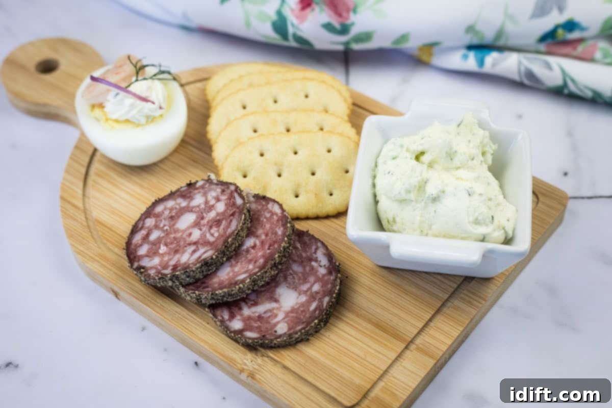 21 Halloween Bites So Good They'll Vanish Before Any Costume Compliments 13 A wooden board with sliced salami, crackers, a deviled egg, and a square dish of homemade Boursin cheese.