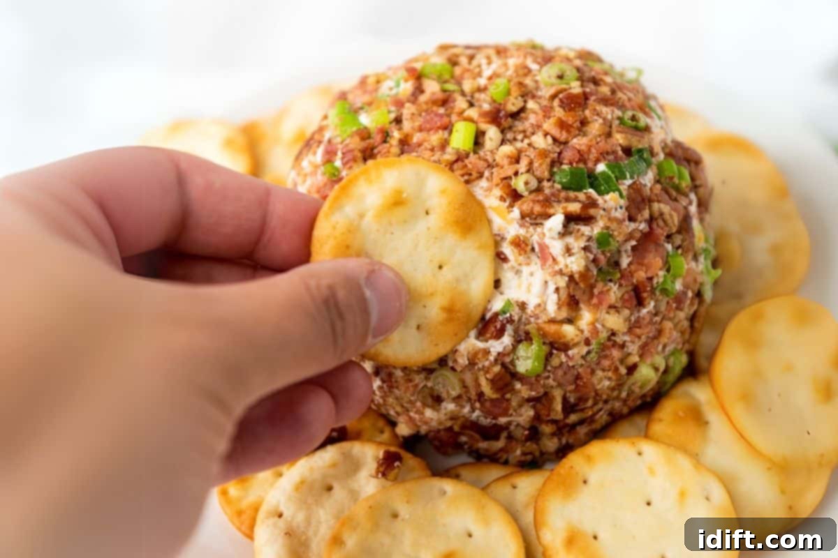 21 Halloween Bites So Good They'll Vanish Before Any Costume Compliments 15 A hand holding a round cracker, reaching to dip into a pecan bacon cheeseball.