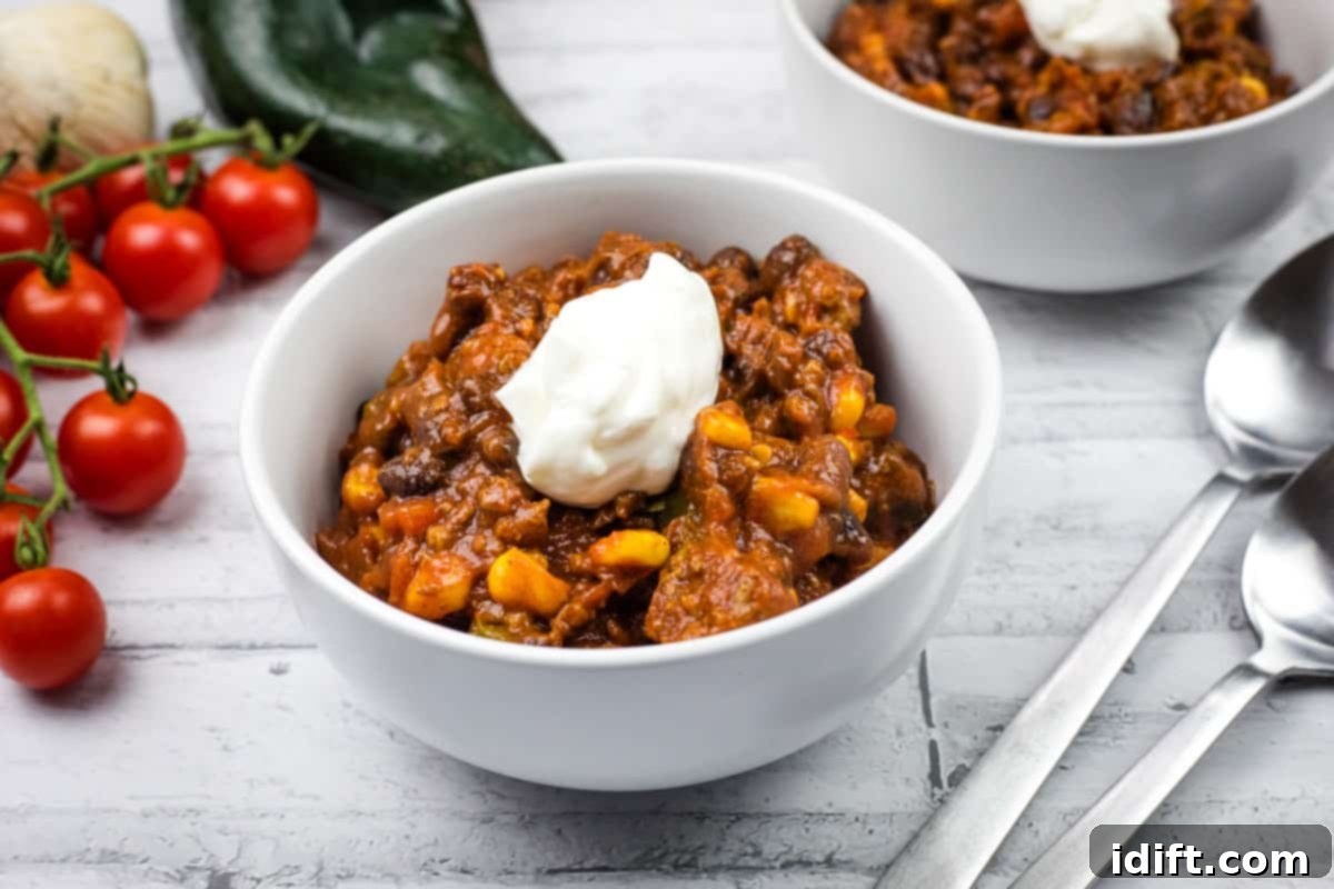 21 Halloween Bites So Good They'll Vanish Before Any Costume Compliments 8 Two white bowls of Southwestern chili topped with sour cream are on a table.