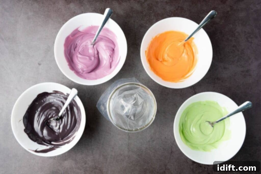 Four bowls containing purple, orange, black, and green melted candies with spoons, arranged around an empty piping bag on a dark surface.