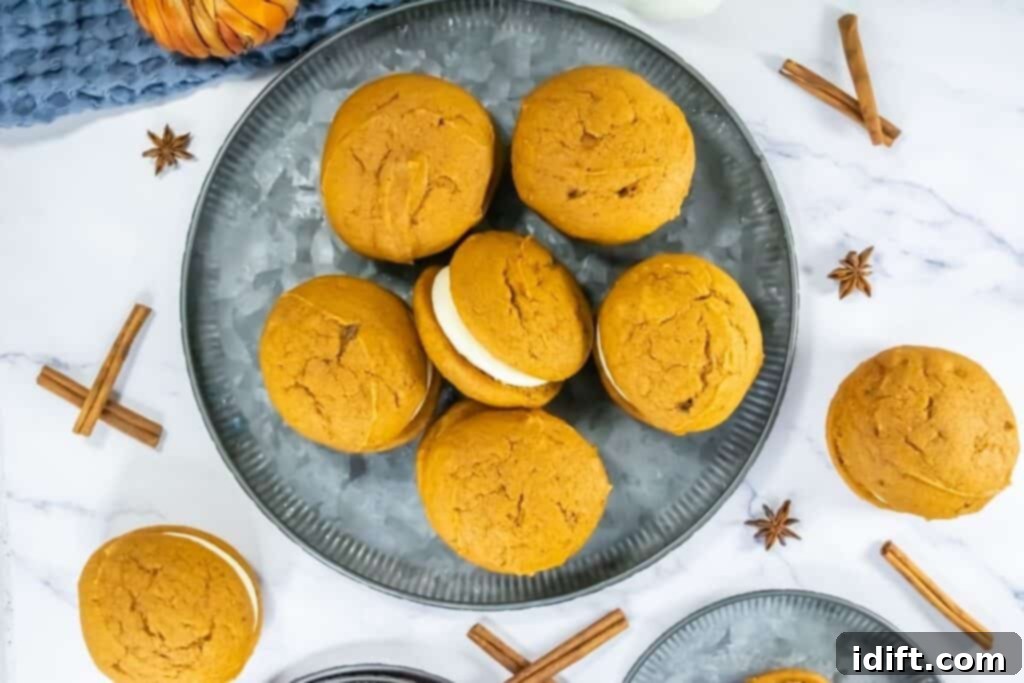 Plate of pumpkin whoopie pies filled with cream frosting, surrounded by cinnamon sticks and star anise.