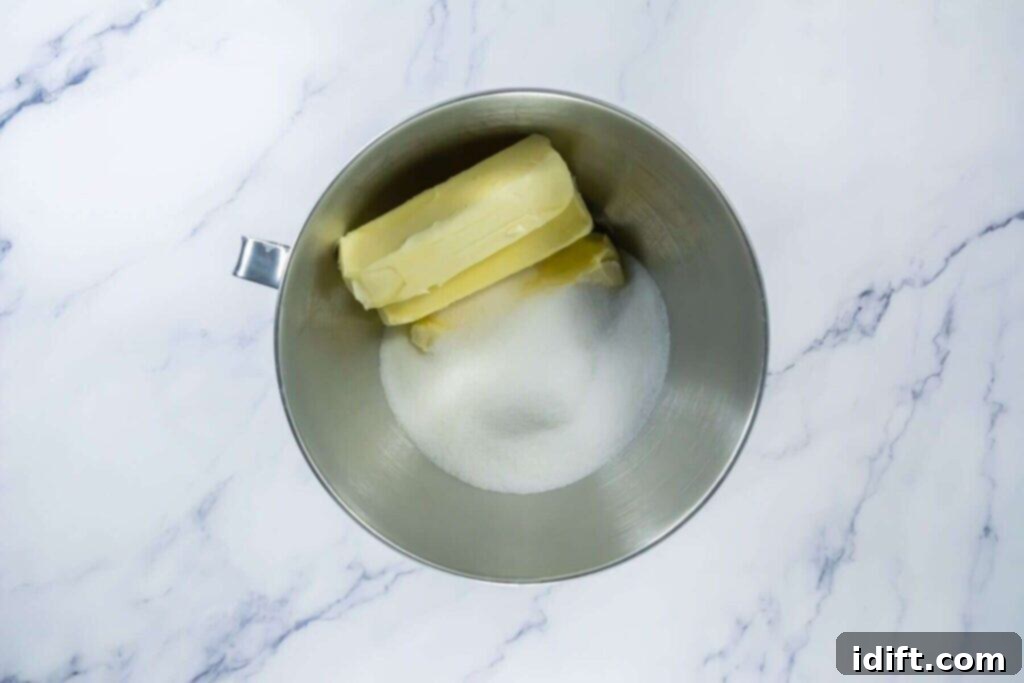 Creamed butter and granulated sugar in a stand mixer bowl on a marble surface.