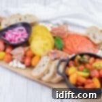 Tomato Flight Selection 5 A wooden board displays sliced tomatoes, cherry tomatoes, pickled onions, mozzarella balls, prosciutto, baguette slices, pine nuts, and basil, with napkins in the background.