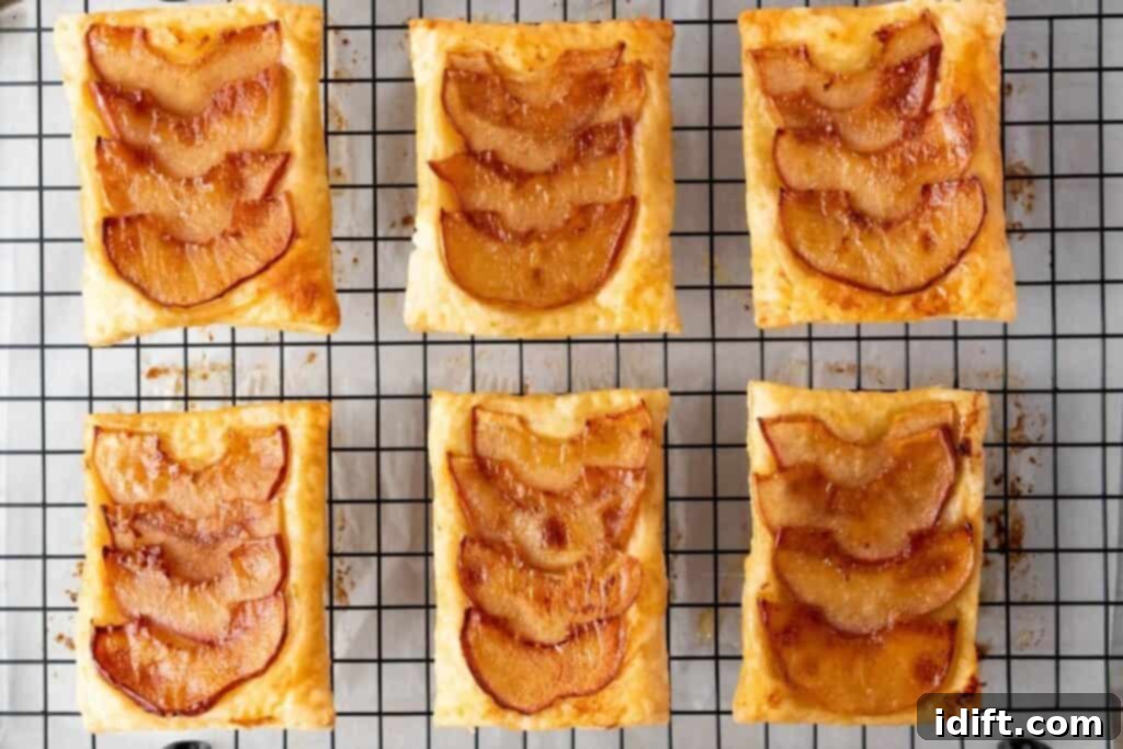 Six rectangular apple tarts with caramelized apple slices on puff pastry, arranged on a cooling rack.