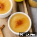 Chef Jenn's Effortless Instant Pot Applesauce 10 Two bowls of applesauce topped with cinnamon sit on a wooden board, next to an apple, a jar of applesauce, and two cinnamon sticks.