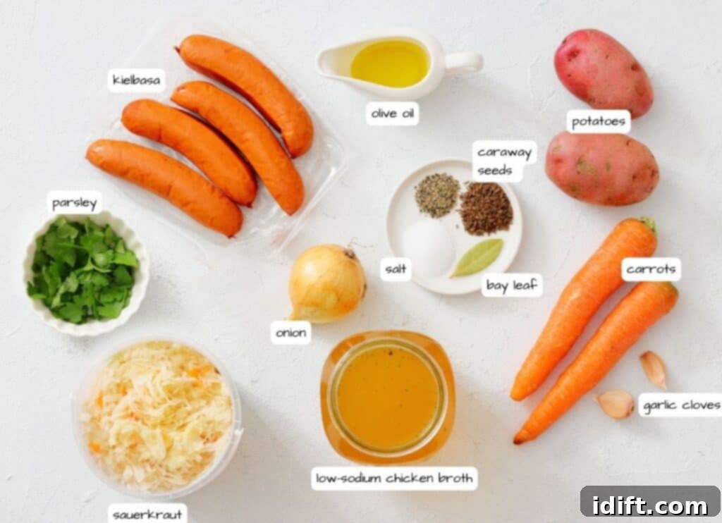 A flat lay of ingredients for a dish, including kielbasa, potatoes, carrots, onion, garlic, sauerkraut, parsley, olive oil, caraway seeds, salt, bay leaf, and chicken broth.