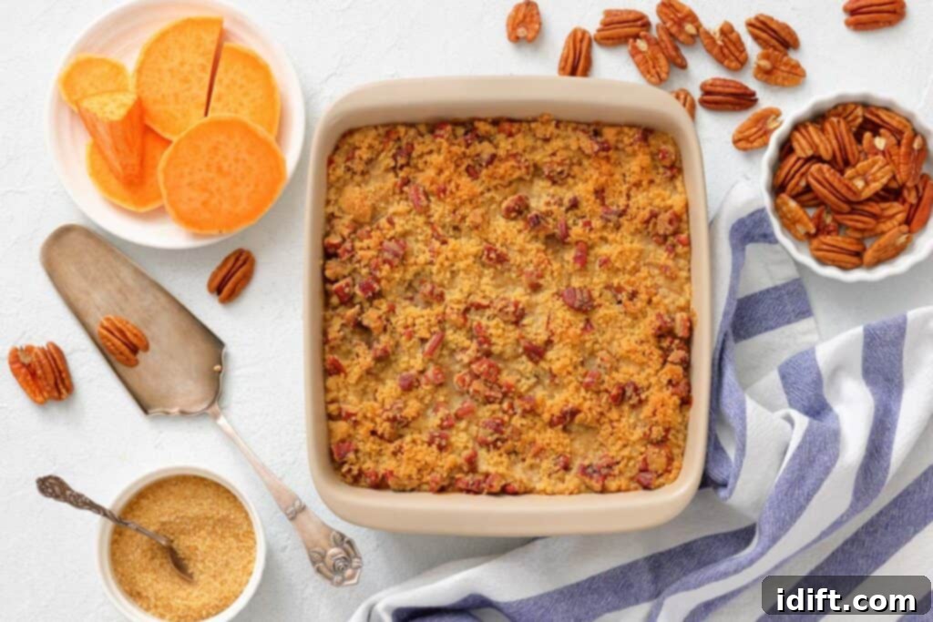 Decadent Sweet Potato Casserole with Crunchy Pecan Streusel 8 A baked sweet potato casserole topped with pecans in a square dish, surrounded by raw sweet potato slices, pecans, brown sugar, and a striped kitchen towel.