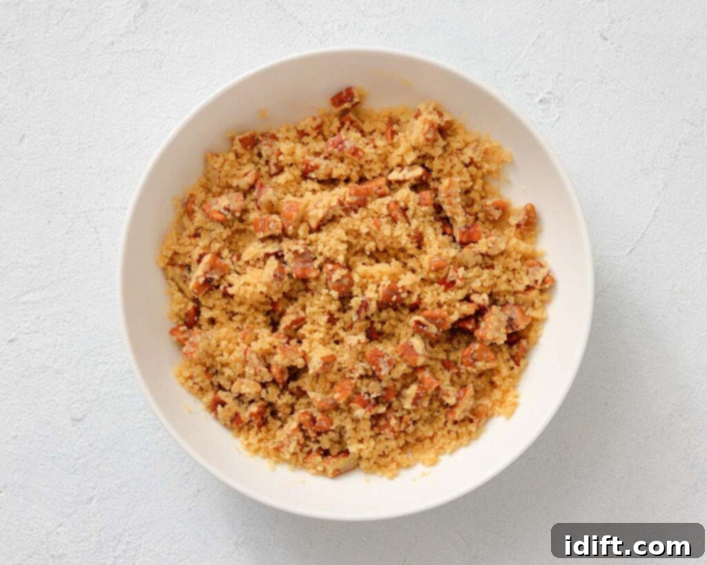 Decadent Sweet Potato Casserole with Crunchy Pecan Streusel 6 A white bowl filled with crumbled bacon mixed with golden brown breadcrumbs on a light surface.