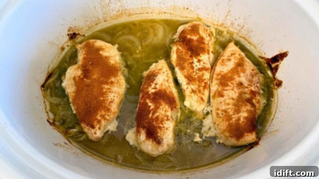 Chicken breasts cooking in a slow cooker with salsa and onions