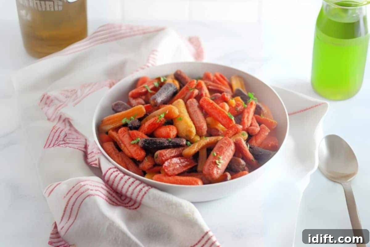 21 Spring-Inspired Dishes to Reinvent Your Week 6 A white bowl filled with honey-roasted baby carrots sits on a white cloth with red stripes, next to a spoon and a green bottle on a light surface.