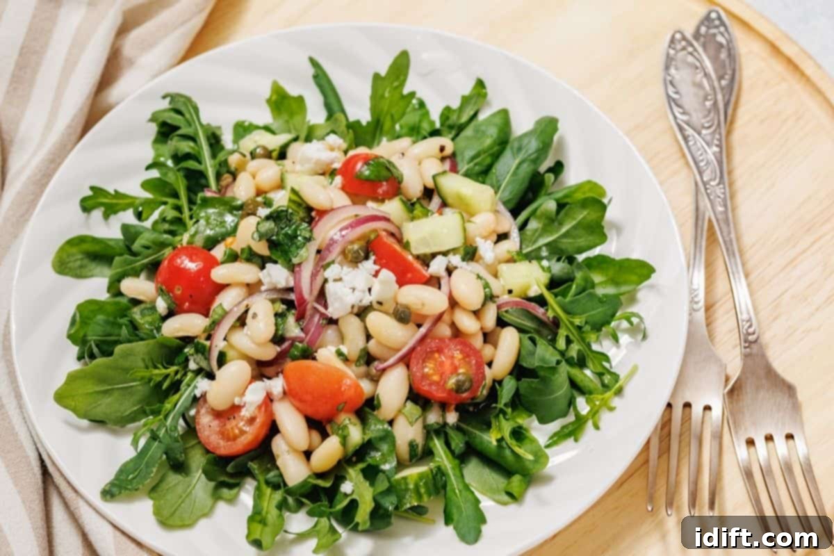 21 Spring-Inspired Dishes to Reinvent Your Week 8 A plate of white bean salad on a wooden surface next to two vintage forks.