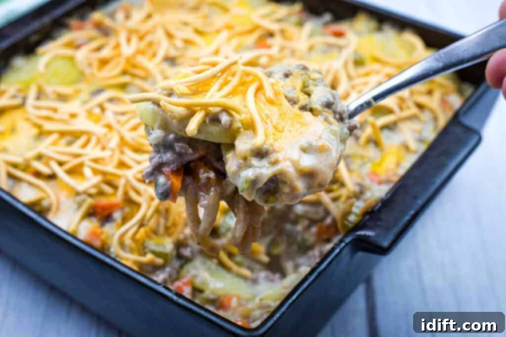 Timeless Kitchen Treasures: Rediscovering Vintage Recipes 8 A spoonful of Church Potluck Hot Dish with Chow Mein Noodles, showcasing its creamy interior and crunchy topping.
